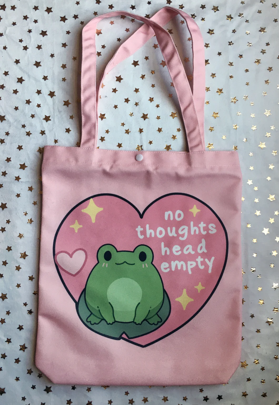 An image of a pink frog tote bag reading 'no thoughts head empty'.