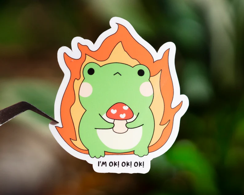 A sticker of a frog using a laptop.